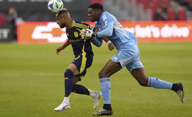 Toronto FC goalkeeper Sean Johnson (1) battles for the ball with Nashville SC's Hany Mukhtar, left, after getting caught outside his area during first-half MLS soccer match action in Toronto, Saturday, May 24, 2025. (Chris Young/The Canadian Press via AP)