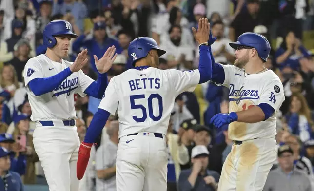 Los Angeles Dodgers' Freddie Freeman, left, Mookie Betts (50) and Max Muncy, right, celebrate after Muncy hit a three-run home run that scored Freeman and Betts in the eighth inning of a baseball game against the Oakland Athletics, Wednesday, May 14, 2025, in Los Angeles. (AP Photo/Jayne Kamin-Oncea)