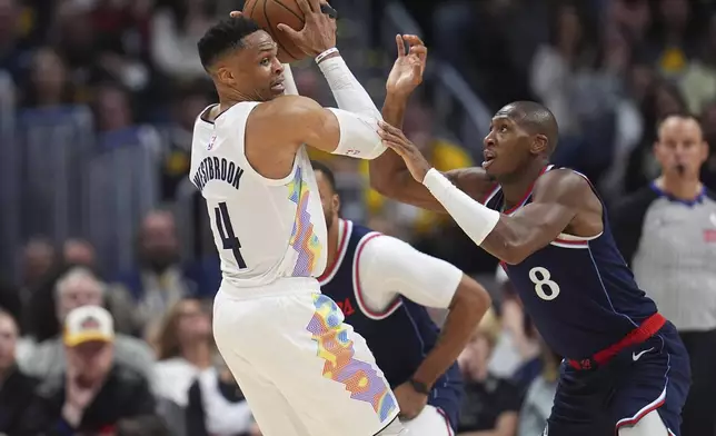 Denver Nuggets guard Russell Westbrook, left, looks to pass the ball as Los Angeles Clippers guard Kris Dunn defends in the second half of Game 5 of an NBA basketball playoff series Tuesday, April 29, 2025, in Denver. (AP Photo/David Zalubowski)