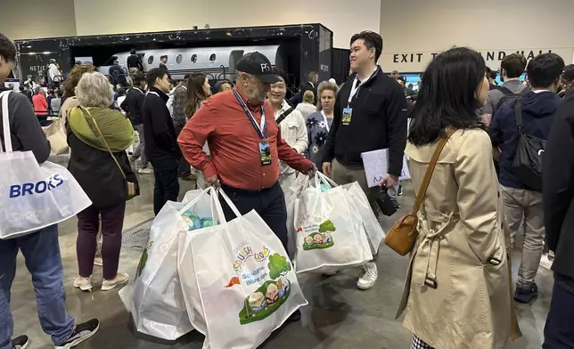Berkshire Hathaway shareholder Devan Bisher holds five large bags filled with Warren Buffett and Charlie Munger Squishmallows while waiting in line on Friday, May 2, 2025 in Omaha, Neb. (AP Photo/Josh Funk)