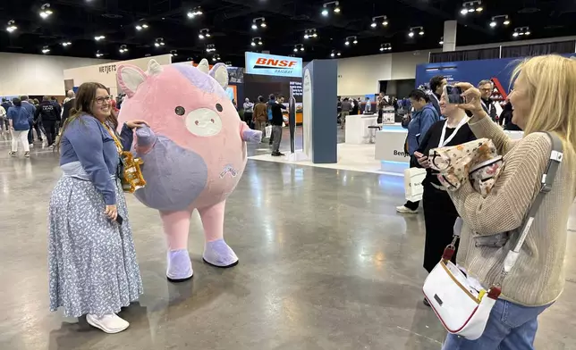 Berkshire Hathaway shareholders pose for photos with life-size Squishmallows ahead of Saturday's annual meeting with Warren Buffett on Friday, May 2, 2025 in Omaha, Neb. (AP Photo/Josh Funk)