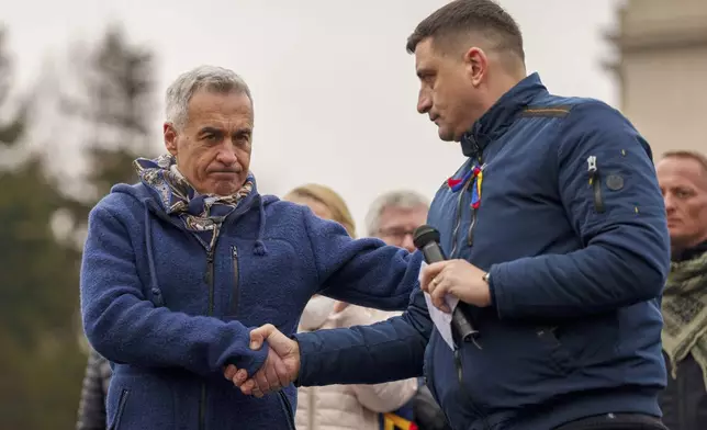FILE - Calin Georgescu, left, the winner of the first round of presidential elections which were annulled, shakes hands with George Simion, presidential candidate for the Alliance for the Union of Romanians (AUR) during a protest calling for the resignation of the country's Prime Minister Marcel Ciolacu, in Bucharest, Romania, Saturday, March 1, 2025. (AP Photo/Andreea Alexandru, File)