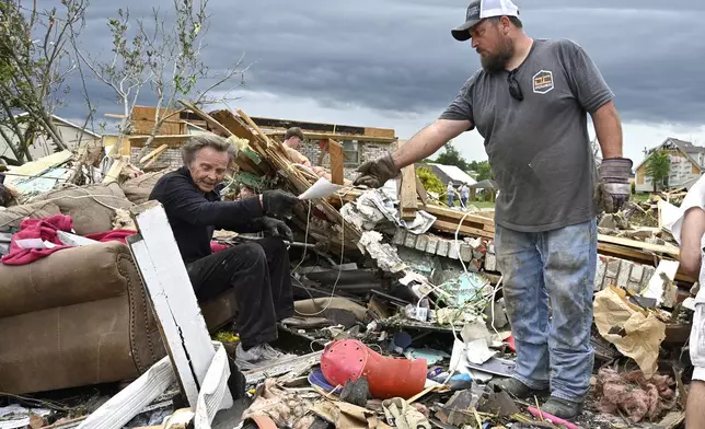 Donovan Queen, right, hands Dam Barnett some photographs that he dug out of the remains of his home in the Sunshine Hills neighborhood in London, Ky., Monday, May 19, 2025. (AP Photo/Timothy D. Easley)