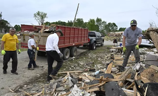 Volunteers load a dump truck with debris during cleanup efforts after severe weather in the Sunshine Hills neighborhood in London, Ky., Monday, May 19, 2025. (AP Photo/Timothy D. Easley)