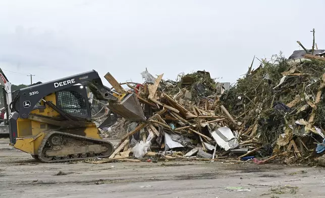 Workers pile debris from storm damage into piles for disposal at the London-Corbin Airport in London, Ky., Monday, May 19, 2025. (AP Photo/Timothy D. Easley)