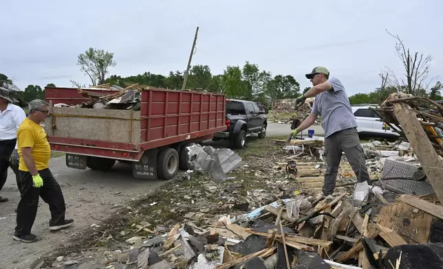 Volunteers load a dump truck with debris during cleanup efforts after severe storms in the Sunshine Hills neighborhood in London, Ky., Monday, May 19, 2025. (AP Photo/Timothy D. Easley)