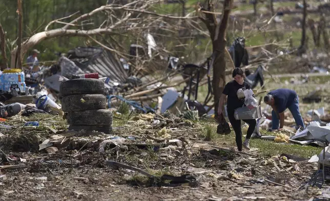 Macey Coffey carries salvageable items from what isleft of Edwina Wilson's destroyed home, Sunday, May 18, 2025, in London, Ky., after a severe storm passed through the area. (AP Photo/Carolyn Kaster)