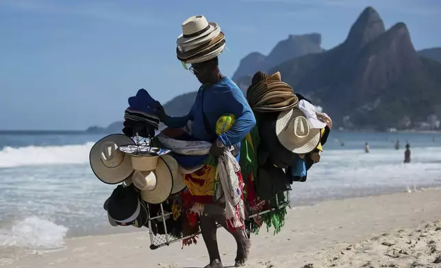 A vendor walks with his hats and beachwear along Ipanema Beach in Rio de Janeiro, Sunday, May 25, 2025. (AP Photo/Bruna Prado)