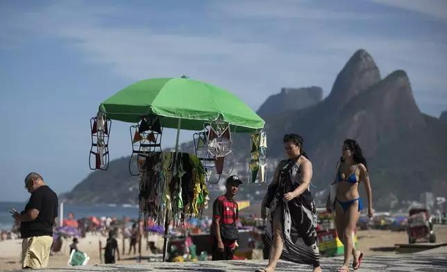 Beachgoers walk past a vendor's stand of beachwear on Ipanema Beach in Rio de Janeiro, Sunday, May 25, 2025. (AP Photo/Bruna Prado)