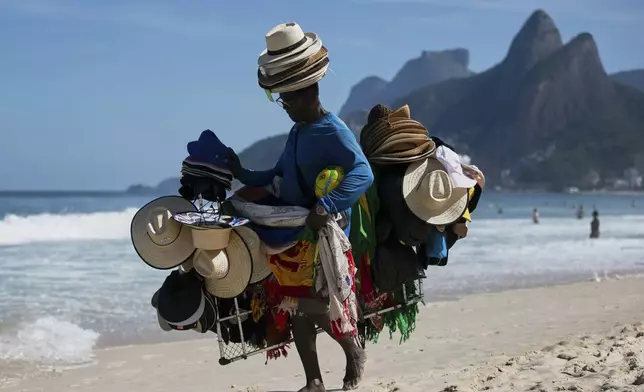 A vendor walks with his hats and beachwear along Ipanema Beach in Rio de Janeiro, Sunday, May 25, 2025. (AP Photo/Bruna Prado)