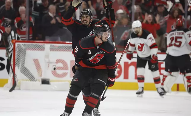 Carolina Hurricanes' Sebastian Aho (20) celebrates his game-winning goal with teammate Seth Jarvis (24) during the second overtime period of Game 5 of an NHL hockey first-round playoff series against the New Jersey Devils in Raleigh, N.C., Tuesday, April 29, 2025. (AP Photo/Karl DeBlaker)