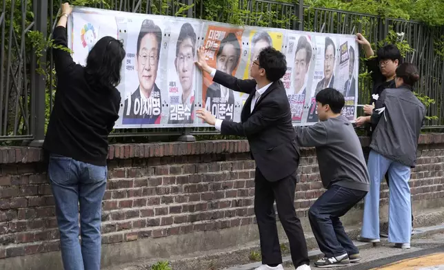 Officials from the election management committee put presidential election posters of candidates in Seoul, South Korea, Thursday, May 15, 2025. (AP Photo/Ahn Young-joon)