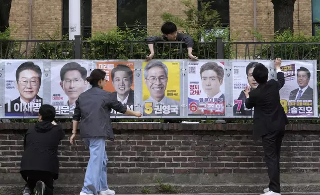Officials from the election management committee put presidential election posters of candidates in Seoul, South Korea, Thursday, May 15, 2025. (AP Photo/Ahn Young-joon)