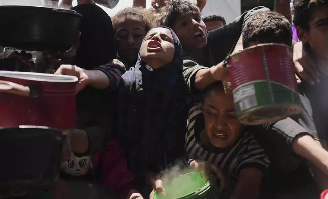 Palestinians struggle to get donated food at a community kitchen in Khan Younis, Gaza Strip, Monday, May 5, 2025. (AP Photo/Abdel Kareem Hana)