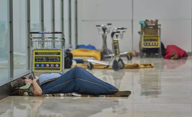 People sleep on the floor of Terminal 4 at Adolfo Suarez-Madrid Barajas Airport in Madrid, Spain, Thursday, May 15, 2025. (AP Photo/Manu Fernandez)