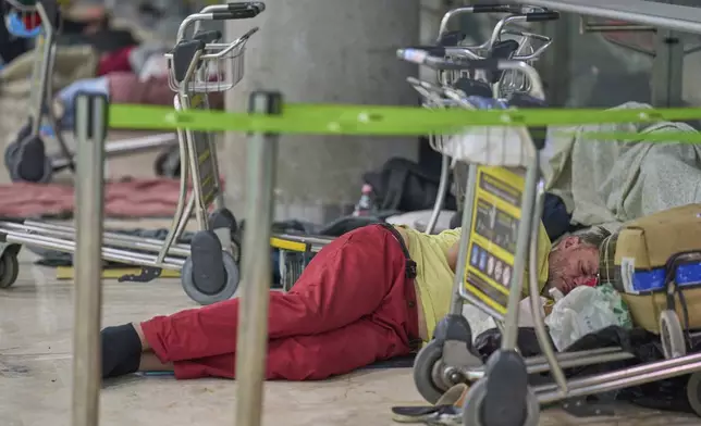A person sleeps on the floor of Terminal 4 at Adolfo Suarez-Madrid Barajas Airport in Madrid, Spain, Thursday, May 15, 2025. (AP Photo/Manu Fernandez)