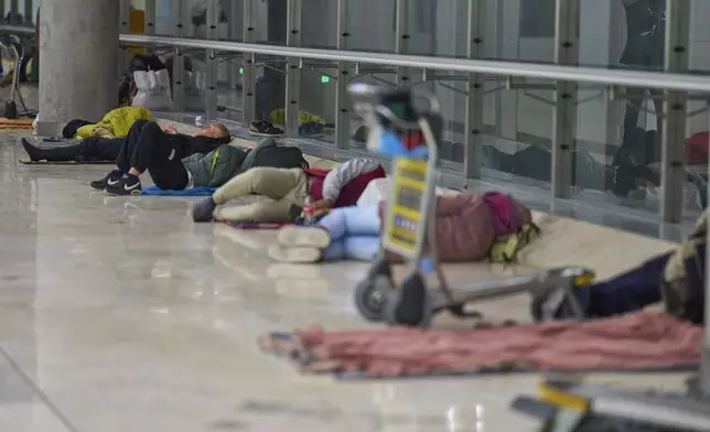 People sleep on the floor of Terminal 4 at Adolfo Suarez-Madrid Barajas Airport in Madrid, Spain, Thursday, May 15, 2025. (AP Photo/Manu Fernandez)