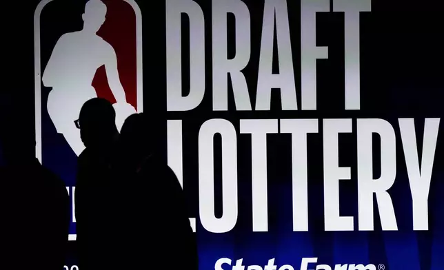 FILE - People walk by a sign during the NBA basketball draft lottery in Chicago, Tuesday, May 16, 2023. (AP Photo/Nam Y. Huh, File)