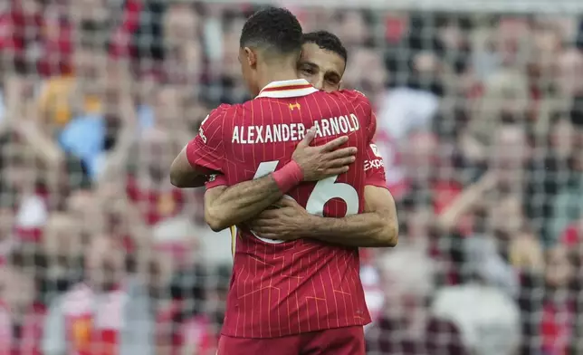 Liverpool's Mohamed Salah hugs teammate Trent Alexander-Arnold to celebrate after scoring his side's first goal during the English Premier League soccer match between Liverpool and Crystal Palace at the Anfield stadium in Liverpool, England, Sunday, May 25, 2025. (AP Photo/Jon Super)