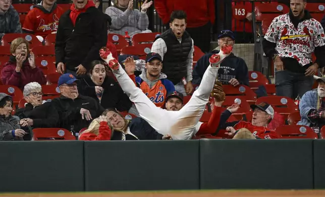 St. Louis Cardinals third baseman Nolan Arenado, center, falls into the stands after catching a foul ball hit by New York Mets' Juan Soto in the eighth inning during the second baseball game of a doubleheader, Sunday, May 4, 2025, in St. Louis. (AP Photo/Joe Puetz)