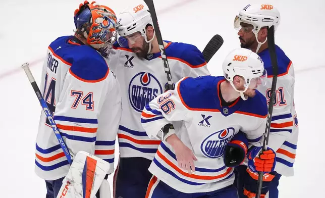 Edmonton Oilers goaltender Stuart Skinner (74) gathers with teammates, from left defenseman Evan Bouchard, defenseman John Klingberg (36) and left wing Evander Kane (91) following a 3-0 win over the Dallas Stars in Game 2 of the Western Conference finals in the NHL hockey Stanley Cup playoffs, Friday, May 23, 2025, in Dallas. (AP Photo/LM Otero)