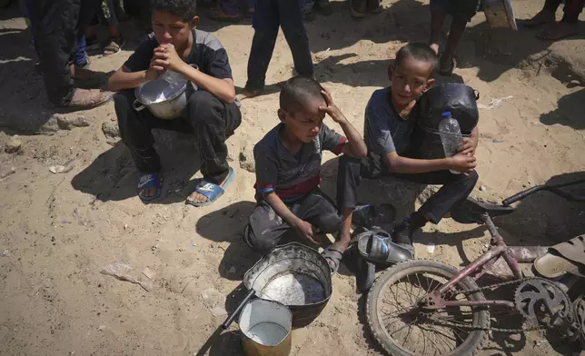 Palestinian children wait to get donated food at a community kitchen in Khan Younis, in the southern Gaza Strip, Friday, May 9, 2025. (AP Photo/Abdel Kareem Hana)