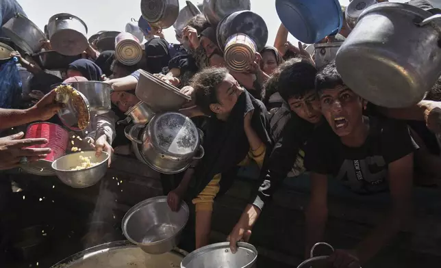 Palestinians struggle to obtain donated food at a community kitchen in Khan Younis, in the southern Gaza Strip, Friday, May 9, 2025. (AP Photo/Abdel Kareem Hana)