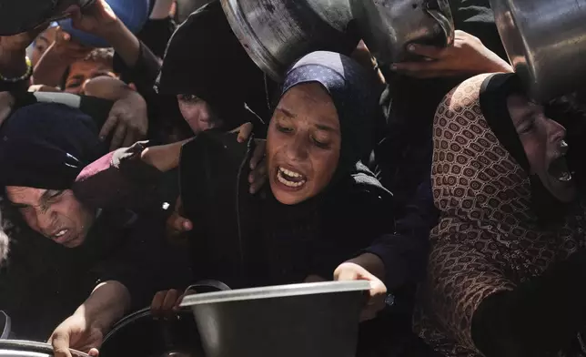 Palestinians struggle to obtain donated food at a community kitchen in Khan Younis, in the southern Gaza Strip, Friday, May 9, 2025. (AP Photo/Abdel Kareem Hana)