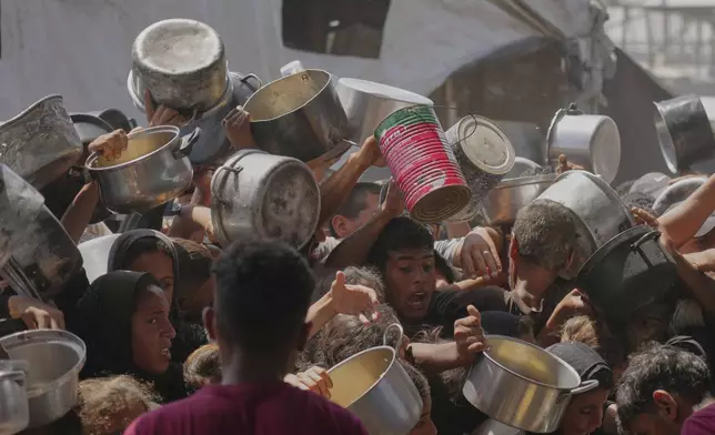 Palestinians struggle to obtain donated food at a community kitchen in Khan Younis, in the southern Gaza Strip, Friday, May 9, 2025. (AP Photo/Abdel Kareem Hana)