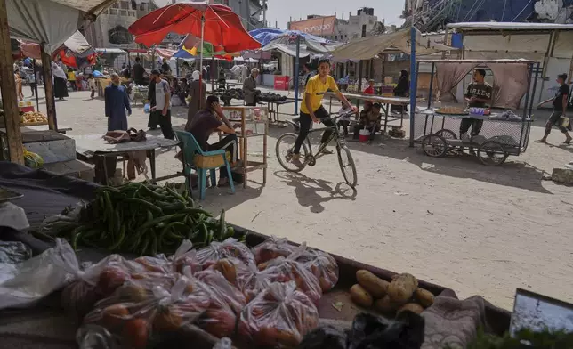 Palestinians purchase goods at a makeshift market in Khan Younis, Gaza Strip, Sunday, May 11, 2025. (AP Photo/Abdel Kareem Hana)