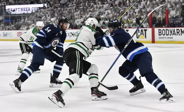 Winnipeg Jets' Neal Pionk (right) checks Dallas Stars' Jamie Benn (14) during first period NHL playoff hockey action in Winnipeg, Thursday, May 15, 2025. (Fred Greenslade/The Canadian Press via AP)