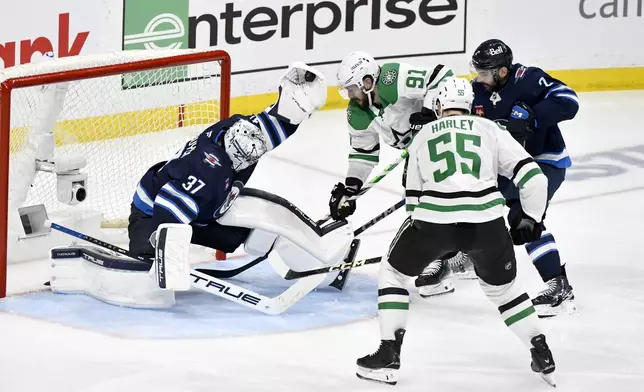 Winnipeg Jets goaltender Connor Hellebuyck (37) makes a save on a Dallas Stars shot as Tyler Seguin (91) and Thomas Harley (55) look for the rebound during second period NHL playoff hockey action in Winnipeg, Thursday, May 15, 2025. (Fred Greenslade/The Canadian Press via AP)
