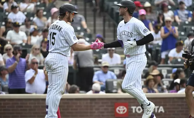 Colorado Rockies' Hunter Goodman (15) and Ryan McMahon (24) celebrate after a one-run home run by McMahon in the eighth inning of a baseball game against the San Diego Padres, Sunday, May 11, 2025, in Denver. (AP Photo/Geneva Heffernan)