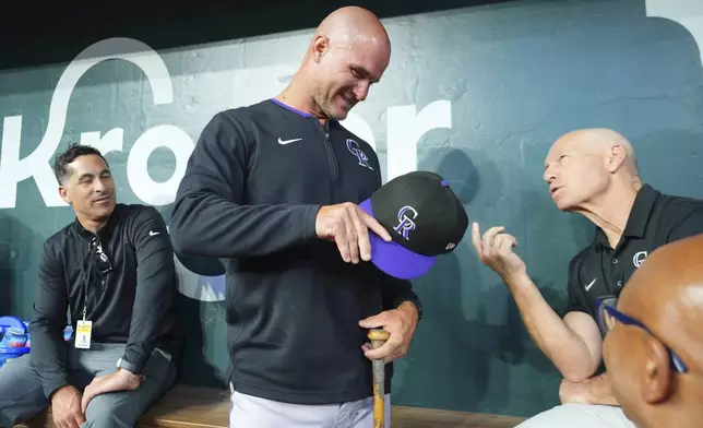 Colorado Rockies interim manager Warren Schaeffer, center, talks in the dugout before a baseball game against the Texas Rangers, Monday, May 12, 2025, in Arlington, Texas. (AP Photo/LM Otero)