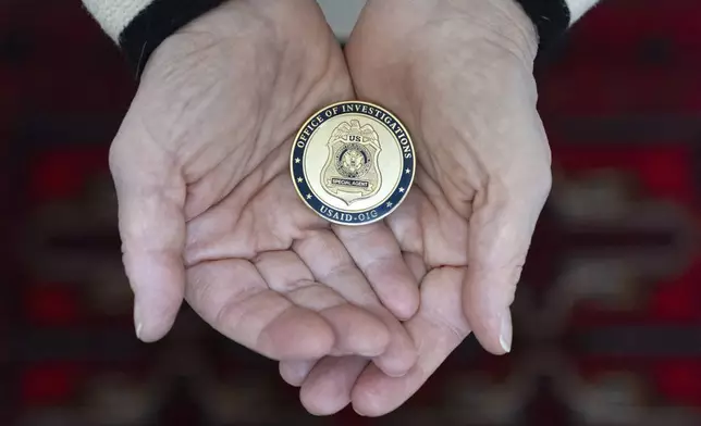 Cathy Votaw, 69, holds a coin from the USAID Office of Investigations, Thursday, Feb. 27, 2025, in Washington. (AP Photo/Jacquelyn Martin)