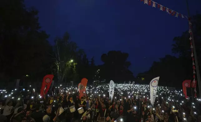 Turkish Cypriot protesters hold the lighted mobile phones aloft as they gather to protest against what they say is Turkey's attempt to erode their secular roots and to strengthen the hold of political Islam over their society, in the northern half of ethnically divided Cyprus' capital Nicosia, on Friday, May 2, 2025. (AP Photo/Petros Karadjias)