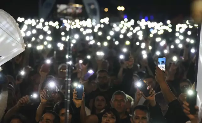 Turkish Cypriot protesters hold the lighted mobile phones aloft as as they gather to protest against what they say is Turkey's attempt to erode their secular roots and to strengthen the hold of political Islam over their society, in the northern half of ethnically divided Cyprus' capital Nicosia, on Friday, May 2, 2025. (AP Photo/Petros Karadjias)