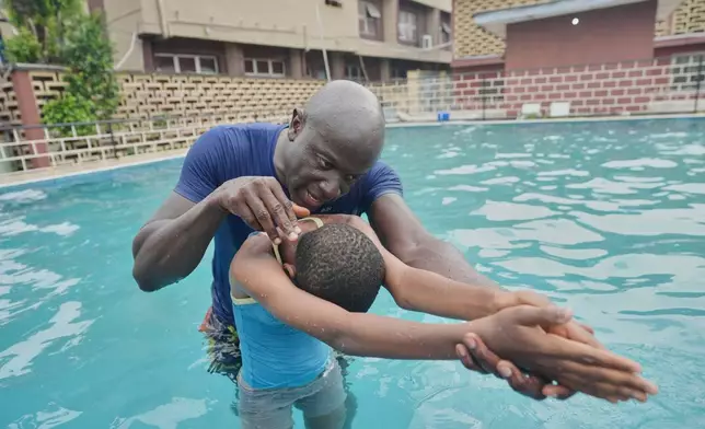 Swimming coach Emeka Chuks Nnadi teaches a disabled student to swim as part of his Swim in 1 Day, or SID, nonprofit, in a pool at the Pacelli School for the Blind and Partially Sighted in Lagos, Nigeria, Wednesday, March 26, 2025. (AP Photo/Sunday Alamba)