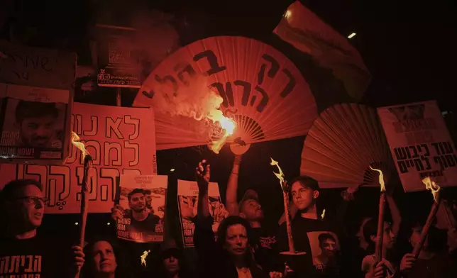 Demonstrators light flares during a protest demanding a cease-fire deal and the immediate release of hostages held by Hamas in the Gaza Strip, Saturday, May 10, 2025, in Tel Aviv, Israel. (AP Photo/Oded Balilty)