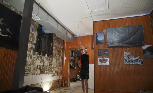 Joey Banz paints the ceiling of his family's RiverWatch Bar &amp; Grill in Chimney Rock Village, N.C., on Wednesday, May 14, 2025. (AP Photo/Allen G. Breed)