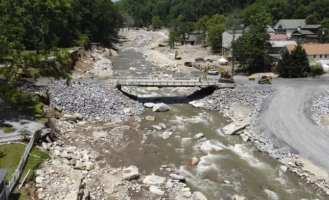 The Broad River flows beneath a temporary bridge beside flood-damaged buildings in Chimney Rock Village, N.C., on Wednesday, May 14, 2025. (AP Photo/Allen G. Breed)