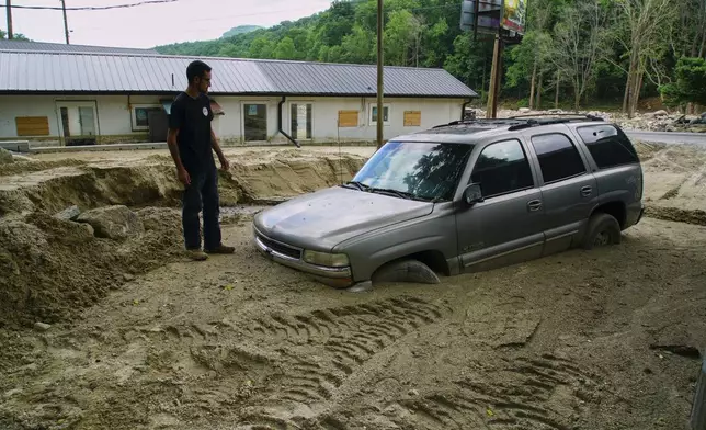 Jonathan Graef stands beside a worker's car engulfed by a slide at his family's Best View Inn in Chimney Rock Village, N.C., on Wednesday, May 14, 2025. He and his siblings were renovating when Hurricane Helene struck and the inn has flooded twice more since. (AP Photo/Allen G. Breed)