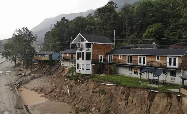 The Carter Lodge hangs precariously over the flood-scoured bank of the Broad River in Chimney Rock Village, N.C., on Tuesday, May 13, 2025. (AP Photo/Allen G. Breed)