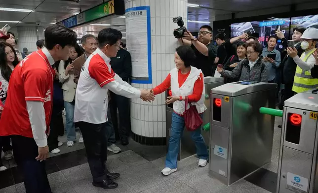 South Korea's People Power Party's presidential election candidate Kim Moon Soo, second from left, shakes hands with a woman during a presidential election campaign at a subway station in Seoul, South Korea, Thursday, May 15, 2025. (AP Photo/Ahn Young-joon)