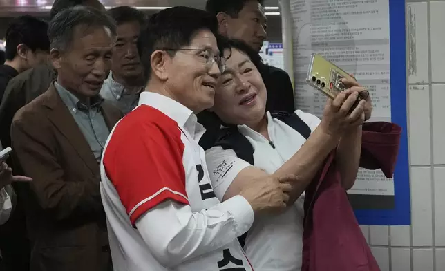 South Korea's People Power Party's presidential election candidate Kim Moon Soo, left, takes a photo with a woman during a presidential election campaign at a subway station in Seoul, South Korea, Thursday, May 15, 2025. (AP Photo/Ahn Young-joon)