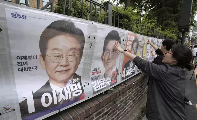Officials from the election management committee put presidential election posters of candidates in Seoul, South Korea, Thursday, May 15, 2025. (AP Photo/Ahn Young-joon)