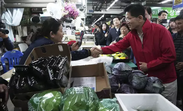 Kim Moon Soo, the presidential candidate of the People Power Party, shakes hands with a woman during a presidential election campaign in Seoul, South Korea, Monday, May 12, 2025. (AP Photo/Lee Jin-man)