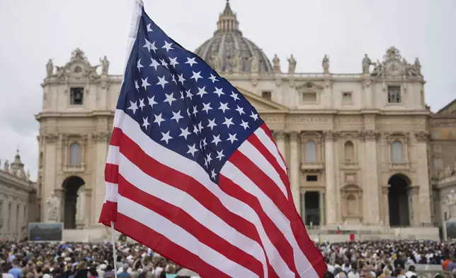 A flag of the United States waves in the crowd as people wait for Pope Leo XIV to appear at the central balcony of St. Peter's Basilica for his first Sunday blessing after his election, in St. Peter's Square at the Vatican, Sunday, May 11, 2025.(AP Photo/Andrew Medichini)