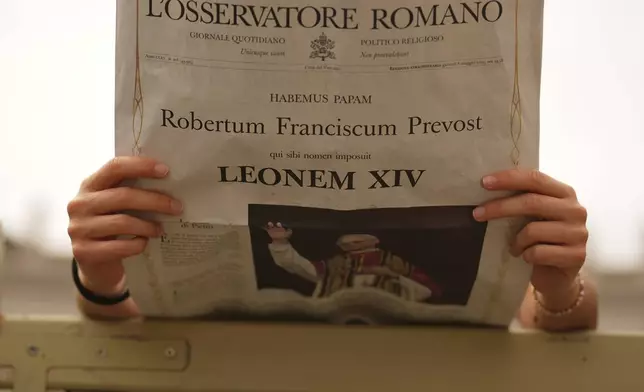 A faithful reads a copy of the Vatican newspaper L'Osservatore Romano with the news of the election of Pope Leo XIV as they wait for him to appear at the central balcony of St. Peter's Basilica for his first Sunday blessing after his election, in St. Peter's Square at the Vatican, Sunday, May 11, 2025.(AP Photo/Andrew Medichini)