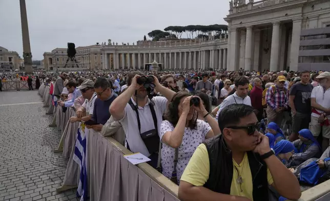 Faithful point their binoculars as they wait for Pope Leo XIV to appear at the central balcony of St. Peter's Basilica for his first Sunday blessing after his election, in St. Peter's Square, at the Vatican, Sunday, May 11, 2025.(AP Photo/Gregorio Borgia)